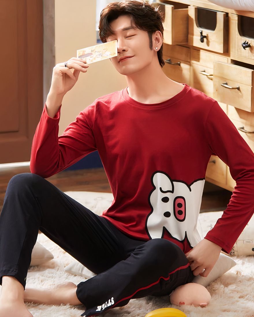 Cotton pajamas with red sweater with pig pattern and black pants worn by a man sitting on a carpet in a house