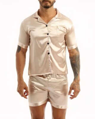 Beige satin pajamas worn by a man tattooed on his left arm, the pajamas are composed of shorts and a shirt with buttons on the front