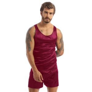 Dark-haired and tattooed man wearing black satin pajamas with a red tank top and matching red shorts