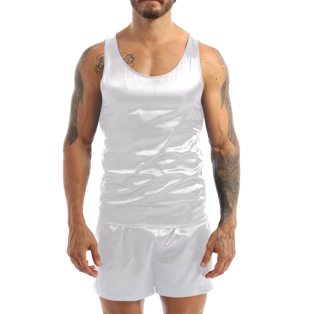 Dark-haired and tattooed man wearing white satin pajamas with a red tank top and matching white shorts