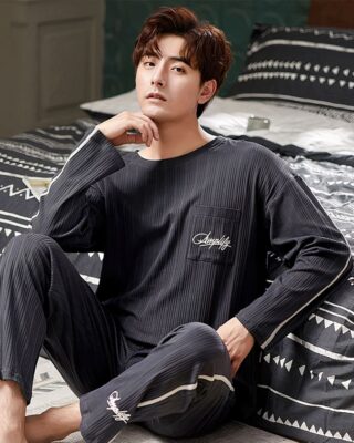 Two-piece long-sleeved pajamas for men with a man wearing the pajamas and a black and white bed background