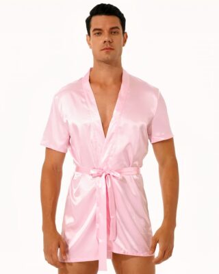 dark-haired man standing and wearing pink satin kimono pajamas tied at the waist with a belt