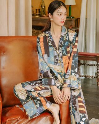 Two-piece satin artist's studio pajamas worn by a woman. The pajamas are multicolored with patterns