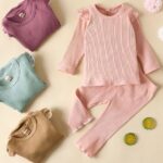 Simple cotton pyjamas for little girls with several pyjamas that are folded and a beige background