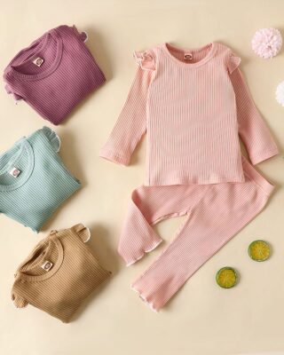 Simple cotton pyjamas for little girls with several pyjamas that are folded and a beige background