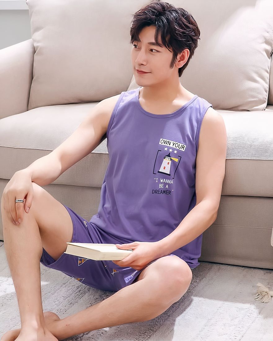Purple cotton sleeveless summer pajamas for men worn by a man sitting on a carpet in front of a chair in a house