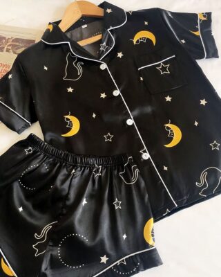 Summer pyjamas in black starry night satin with a white background and a newspaper