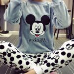 Pyjamas two pieces with the effigy of Mickey, the top is a gray sweater with the head of Mickey and the bottom is a pair of pants composed of head of Mickey black, it is worn ar a young woman