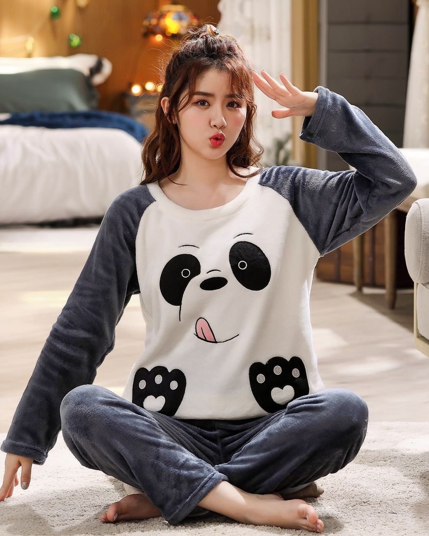 Fleece pajamas with a unisex blue and white panda head worn by a smiling young woman