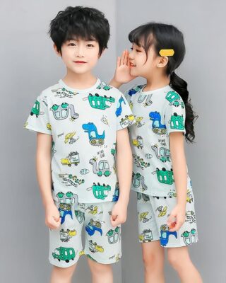 Green two-piece pajamas with cartoon print for children with two children wearing the pajamas and a gray background