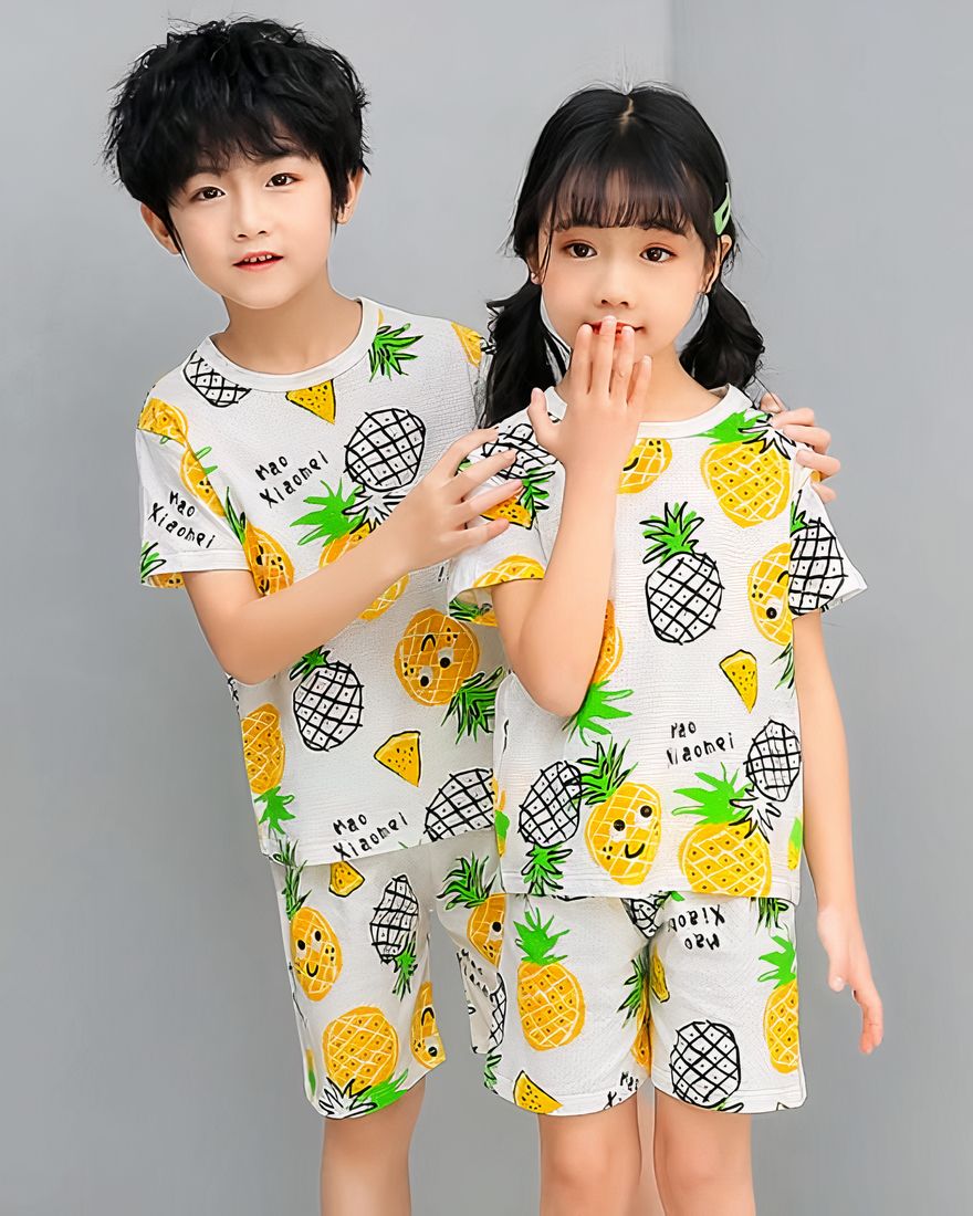 White two-piece pineapple pajamas with two children wearing the pajamas and a gray background
