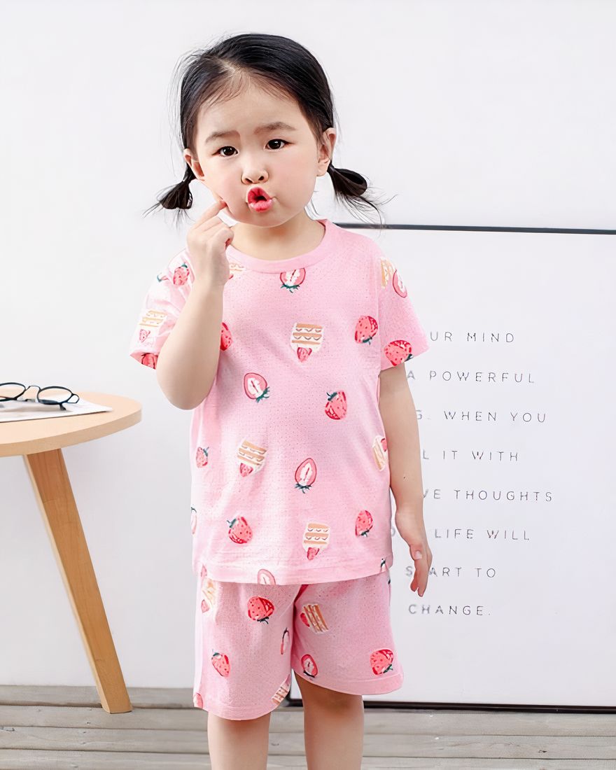 Pink two-piece strawberry pajamas for little girl with a cute little girl wearing the pajamas