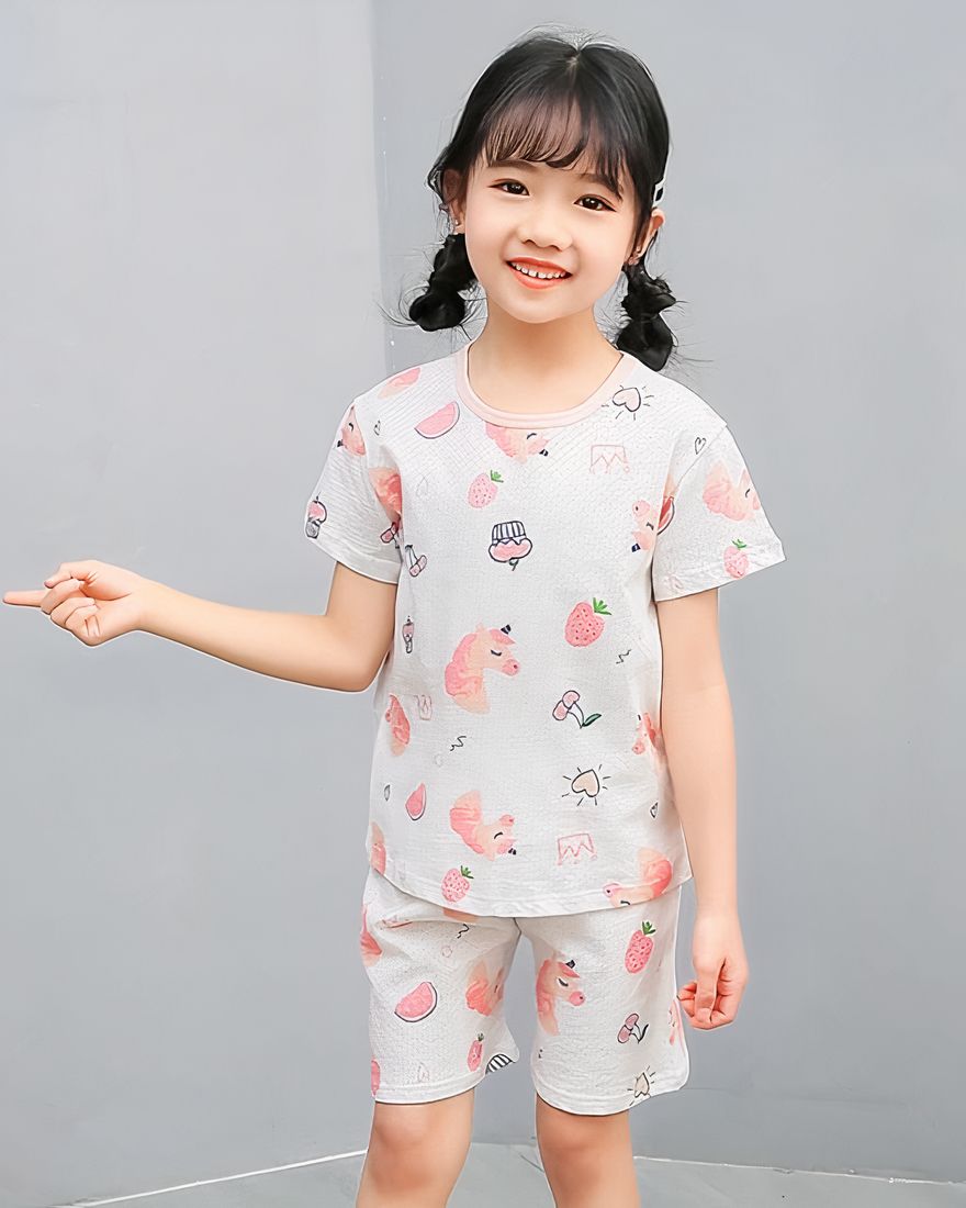 White two-piece pajamas with cartoon pattern for little girl with a little girl wearing the pajamas and a gray background