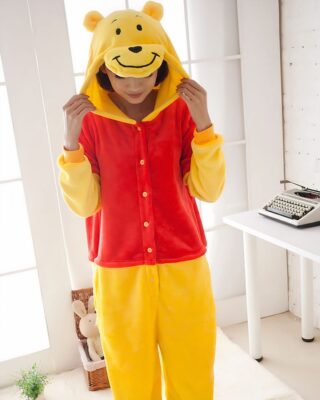 Winnie the Pooh jumpsuit with a woman wearing the pajamas with the hood of the pajamas on her head