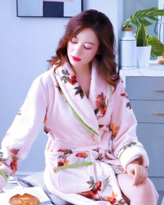 Women's floral print fleece pajamas worn by a woman sitting on a bed in a house