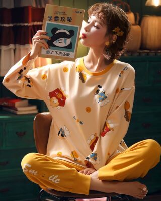 Fall pajamas with sweater and yellow pants for women worn by a woman reading a book sitting on a chair