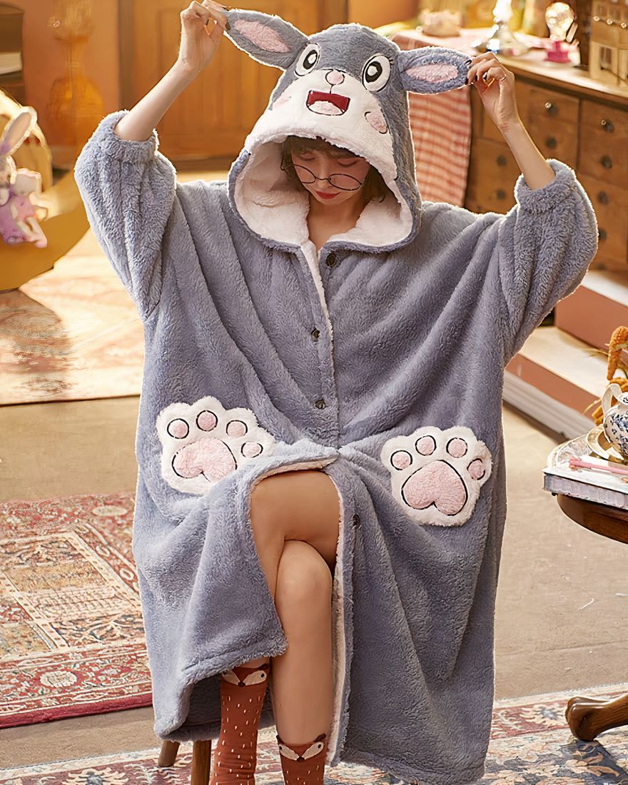 Women's grey hooded fleece pajamas with a woman wearing the pajamas sitting in a chair, with several objects
