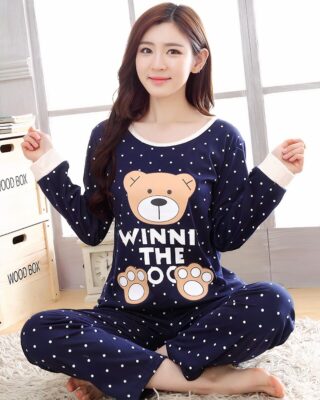 Navy blue and white fall pajamas with Winni the bear pattern for women worn by a woman in a house