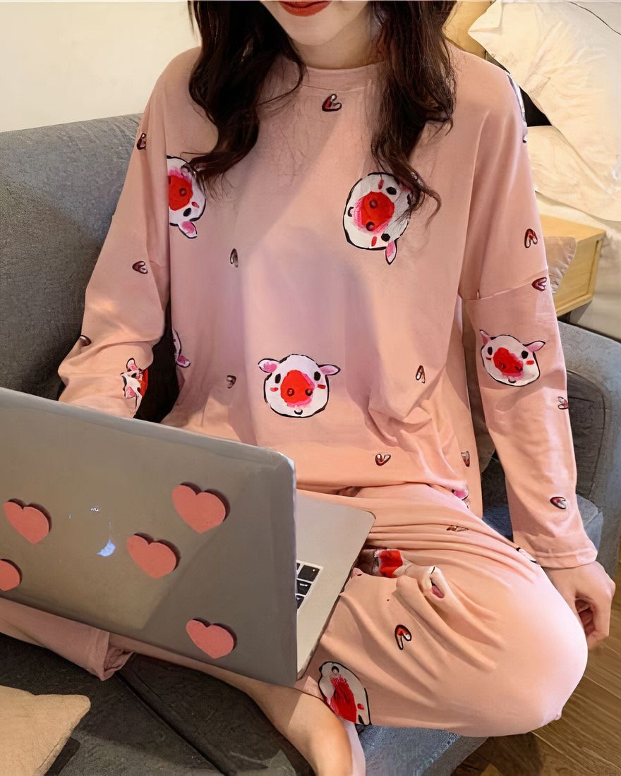 Long-sleeved fall pajamas with pig print worn by a woman sitting on a chair in a house