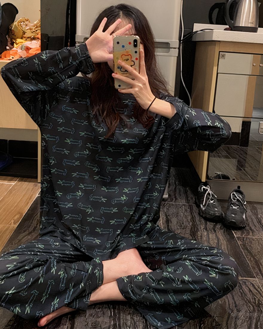 Two-piece fall pajamas with crocodile pattern for women worn by a woman sitting on a carpet in a house