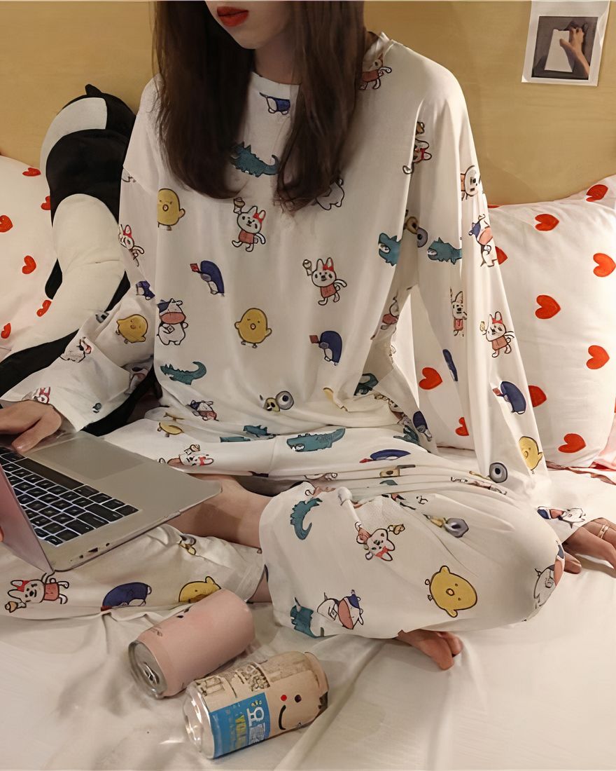 White fall pajamas with cartoon pattern for women worn by a woman on a bed in a house