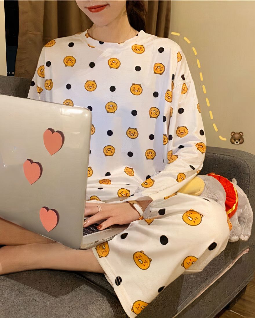 Long-sleeved fall pajamas with orange print worn by a woman sitting on a sofa in a house