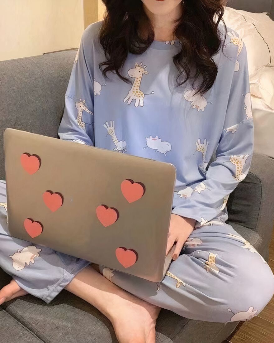 Giraffe and hippopotamus fall pajamas worn by a woman sitting on a chair with a computer in a house