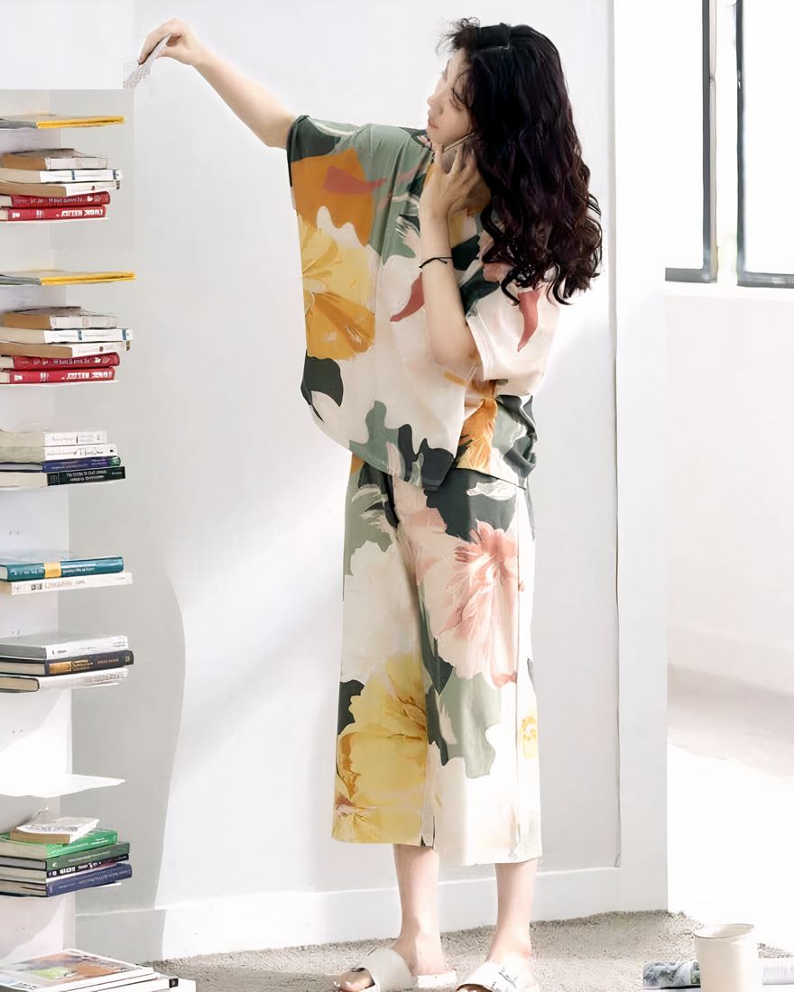 Batwing sleeve summer pajamas with floral print worn by a woman taking a book in a house