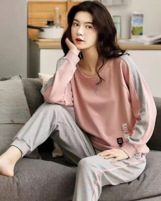 Summer pajamas with pink sweater and gray pants for women worn by a woman sitting on a chair in a house