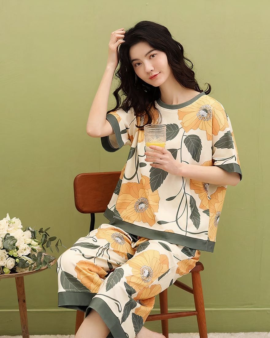 Women's two-piece pyjamas with bat sleeve and fashionable flower pattern worn by a woman sitting on a chair in a house