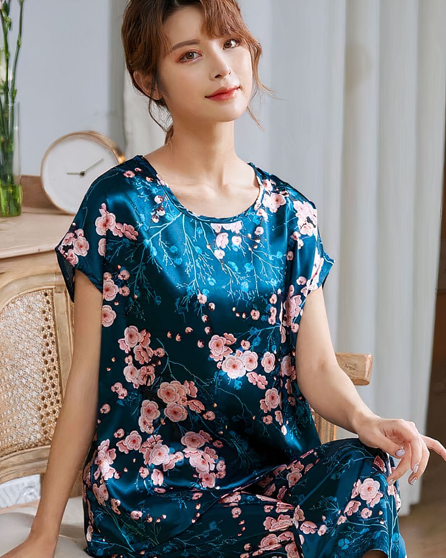 Two-piece silk satin summer pajamas for women sitting on a chair in a house