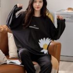 Women's winter pajamas in black satin with a woman who protects the pajamas in the sofa