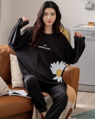 Women's winter pajamas in black satin with a woman who protects the pajamas in the sofa