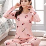 Comfortable and soft two-piece pyjamas for women in pink fashion worn by a woman in front of a bed in a house