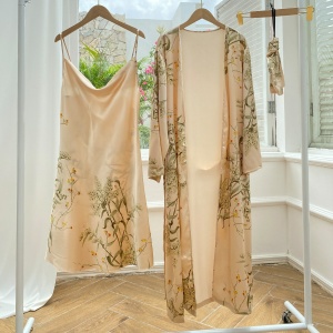 Sexy beige pyjamas with floral print hanging on hangers in a room with wooden floor and white wall and in front of an open window