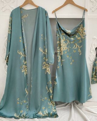 Sexy green pajamas with floral print hanging on hangers in front of a white wall with moldings and on a white sheet