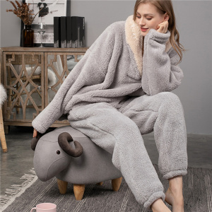 Grey fleece pajamas worn by a woman sitting on a sheep-shaped seat in a living room with grey walls and floors