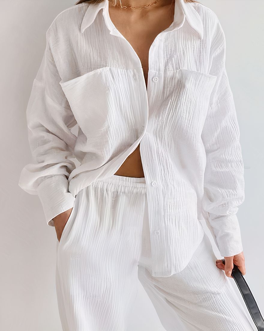 White cotton pajamas worn by a woman against a white wall